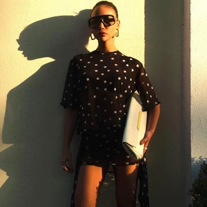Detailed view of women's black and white polka dot mini dress with sheer fabric and sash