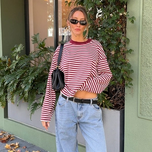 Outdoor street view of a red and white striped long sleeve T-shirt with denim jeans