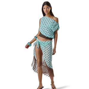 Detail of teal polka dot two-piece set featuring long brown fringes and wrap-style skirt