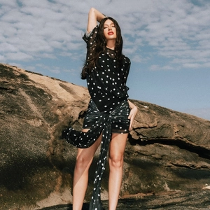 Detail of a sheer black polka dot dress featuring elegant waist ribbons and wrap skirt