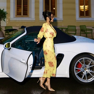 Floral chiffon V-neck dress with long sleeves and belted waist shown by a luxury car