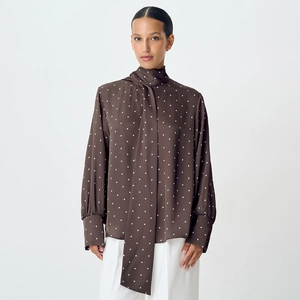 Close-up of brown polka dot satin shirt with elegant tie-neck and lantern sleeves