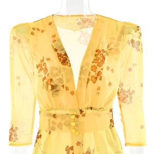 Detailed view of the deep V-neckline and decorative buttons on a yellow floral chiffon dress