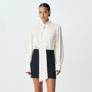 Detail of white polka dot blouse with elegant bow tie neckline and cuffed sleeves