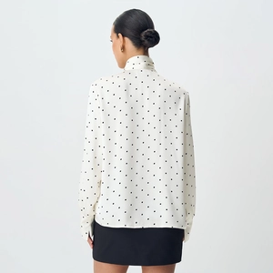 Detailed back view of white polka dot blouse featuring a high neck tie and elegant cuffs