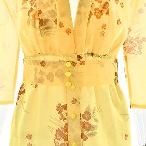 Detail of yellow floral chiffon dress featuring a deep V-neck and decorative yellow buttons