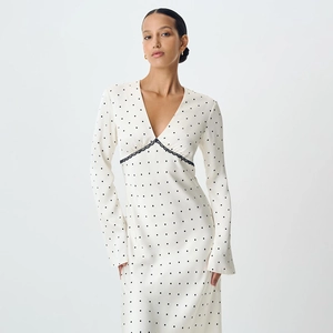 Detail of V-neck white polka dot dress with black lace waist and satin texture finish