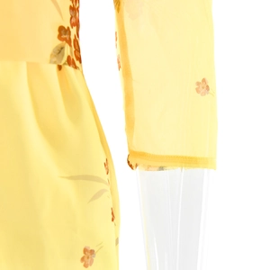 Detail view of lightweight yellow chiffon fabric with delicate orange floral patterns