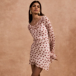 Detailed view of pink polka dot dress with long sleeves and elegant floral shoulder decor