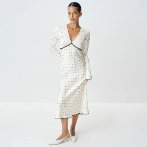 Close-up of elegant V-neckline with black lace trim on cream polka dot satin dress