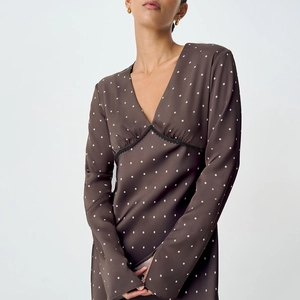 Detail of elegant V-neckline with black lace trim on brown polka dot satin dress
