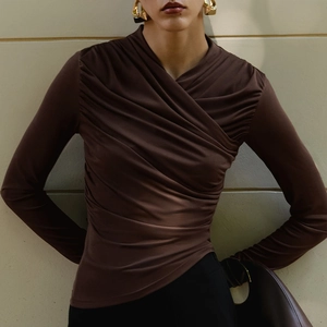 Detail view of the draped ruched design and texture on a chocolate brown slim-fit top