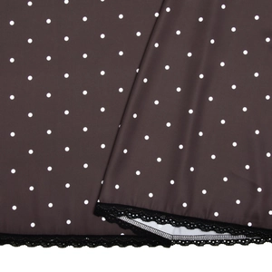 Detailed view of dark polka dot satin fabric with elegant black lace trim on the hemline