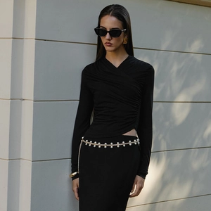 Detail of slim fit long sleeve top with irregular hem and decorative gold pearl chain belt