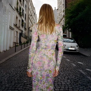 Détail d'une robe maxi florale à manches longues avec boutons et fente haute élégante