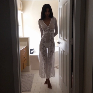 Detail of elegant white sheer lace long-sleeved dress with deep V-neck and floral pattern