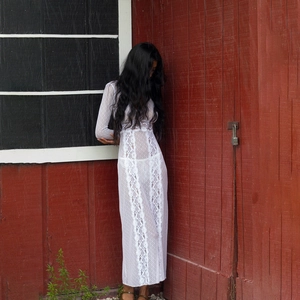 Close-up of elegant white long sleeve lace dress featuring intricate sheer hollow out details