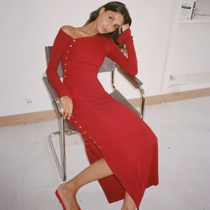 Détail de la robe rouge ajustée avec boutons argentés et une fente latérale haute