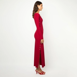 Détail de la robe rouge élégante à manches longues avec boutons en métal et fente latérale