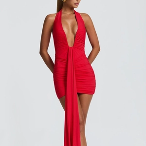 Detail of red deep V-neck ruched dress featuring a long flowing decorative streamer