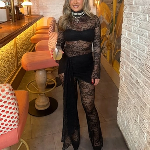 Detail of long sleeve lace jumpsuit showing floral patterns and waist sash detail