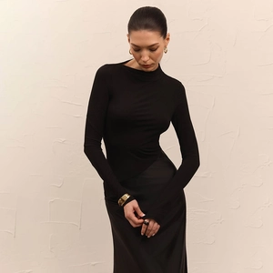 Detail of slim fit black long sleeve dress with high neck against a textured wall