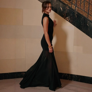 Detail of elegant black slim-fit evening dress with fishtail hem on marble stairs