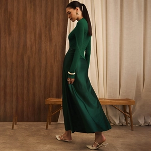 Detail of elegant dark green maxi dress with ribbed knit top and flowing satin skirt