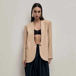 Macro detail of chic beige collarless blazer showing single button and structured shoulders