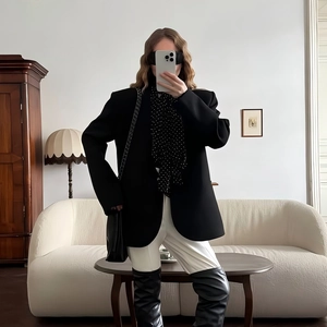Fashionable urban outfit with black blazer, white trousers, and chic over-the-knee boots