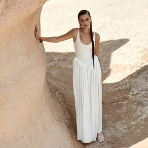 Detail view of a white backless maxi dress featuring a u-neck and pleated skirt in the desert