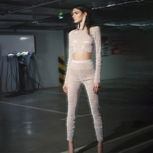 Detailed view of white mesh fabric featuring shimmering rhinestones on slim-fit trousers