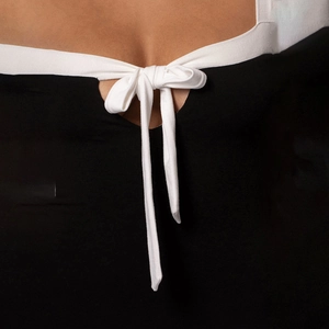 Detail of a black bodycon dress featuring white lace-up straps and a bow tie neckline