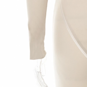 Gros plan sur le tissu en maille côtelée beige et les coutures décoratives du body ajusté