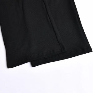 Close-up of the ribbed knit fabric and double-needle hem on black flared trousers