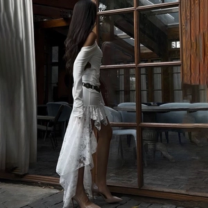 Detail of white lace ruffled hem and asymmetrical fringe design on long sleeve dress