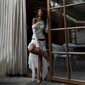 Detail of white off-shoulder mini dress featuring pleated waist and lace hemline