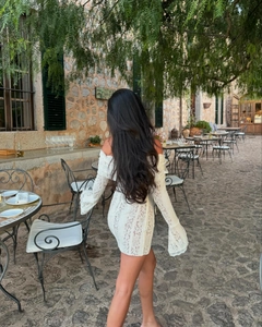 Détail de robe en dentelle blanche avec col bardot et manches longues évasées en cloche