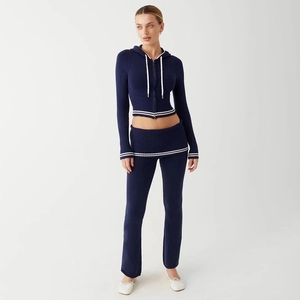 Detail of dark blue knit sports set featuring white striped trim and flared pants design