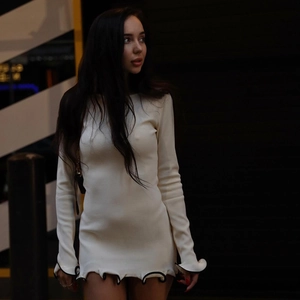 Detail of white slim fit mini dress with black edged ruffle hem and sleeve cuffs