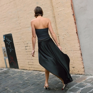 Vista posteriore di un'elegante gonna lunga in raso nero con orlo fluido in stile street