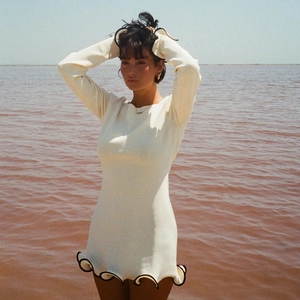 Detail of ruffled black edges on cream long sleeve knit dress with contrast wave hem and cuffs
