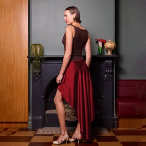 Dettaglio della gonna asimmetrica in raso bordeaux con texture liscia e finitura lucida