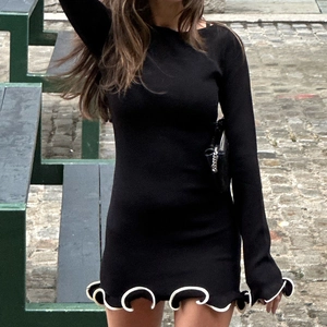 Slim fit black knitted mini dress with long sleeves and white trimmed ruffle hemline