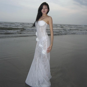Detail of white lace strapless fishtail dress with 3D floral accents on beach