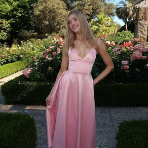 Detail of elegant pink satin maxi dress featuring a deep V-neck and thin shoulder straps