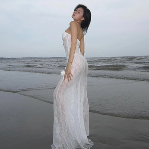 Elegant white strapless lace maxi dress with mermaid hem shown in a coastal setting