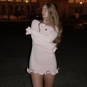 Close-up of wavy ruffled edges with contrast trim on the pink knit long sleeve dress