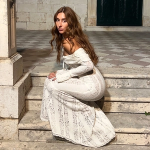 Dettaglio di un elegante abito in pizzo bianco con spalle scoperte e maniche lunghe