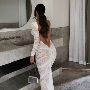 Detail of white lace long sleeve dress featuring an open back and ruffled mermaid hem